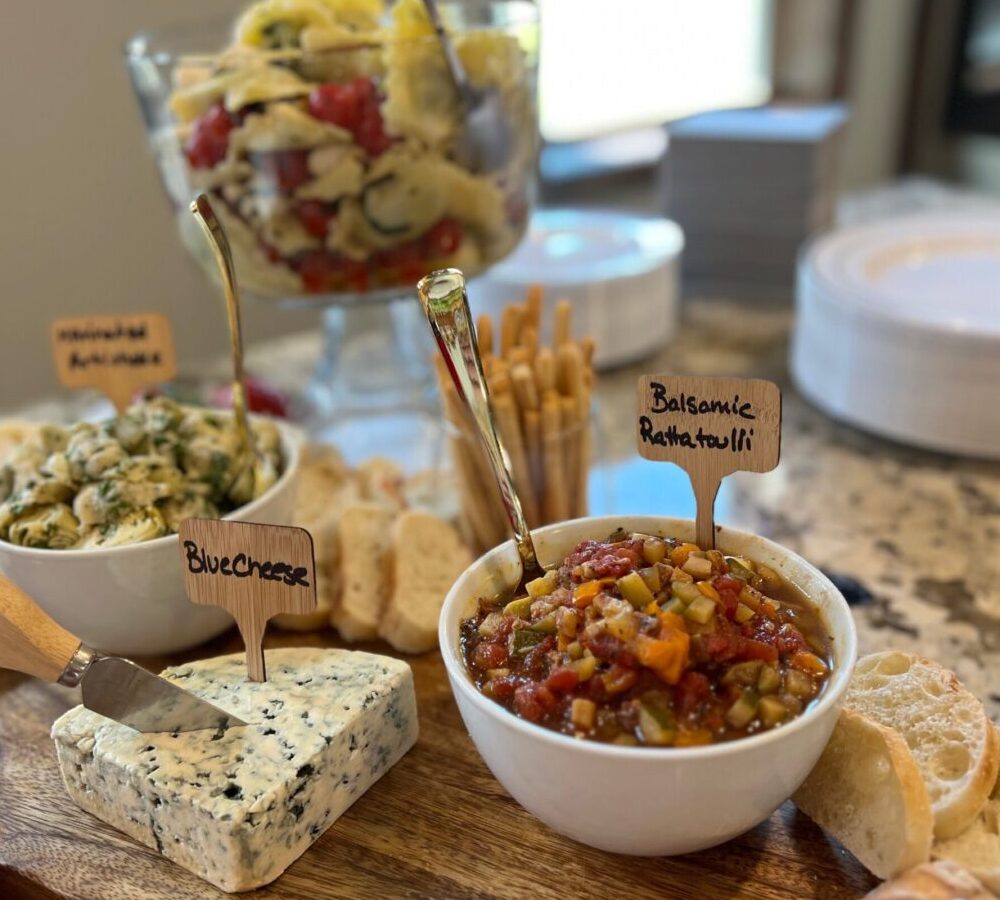 A charcuterie board with cheese, dips, and snacks.