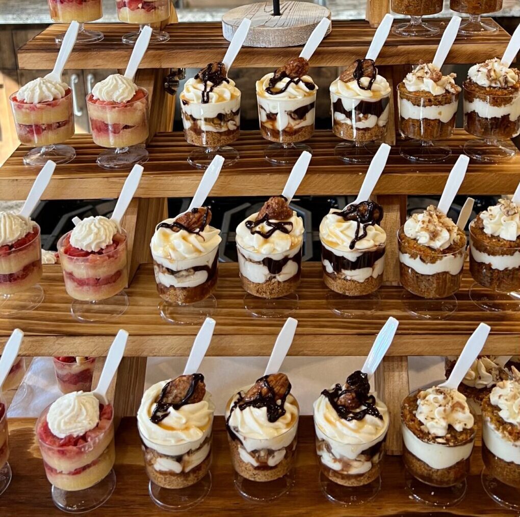 Rows of assorted layered desserts in small cups with spoons.