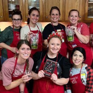 Group of women smiling and holding books in a cozy indoor setting.
