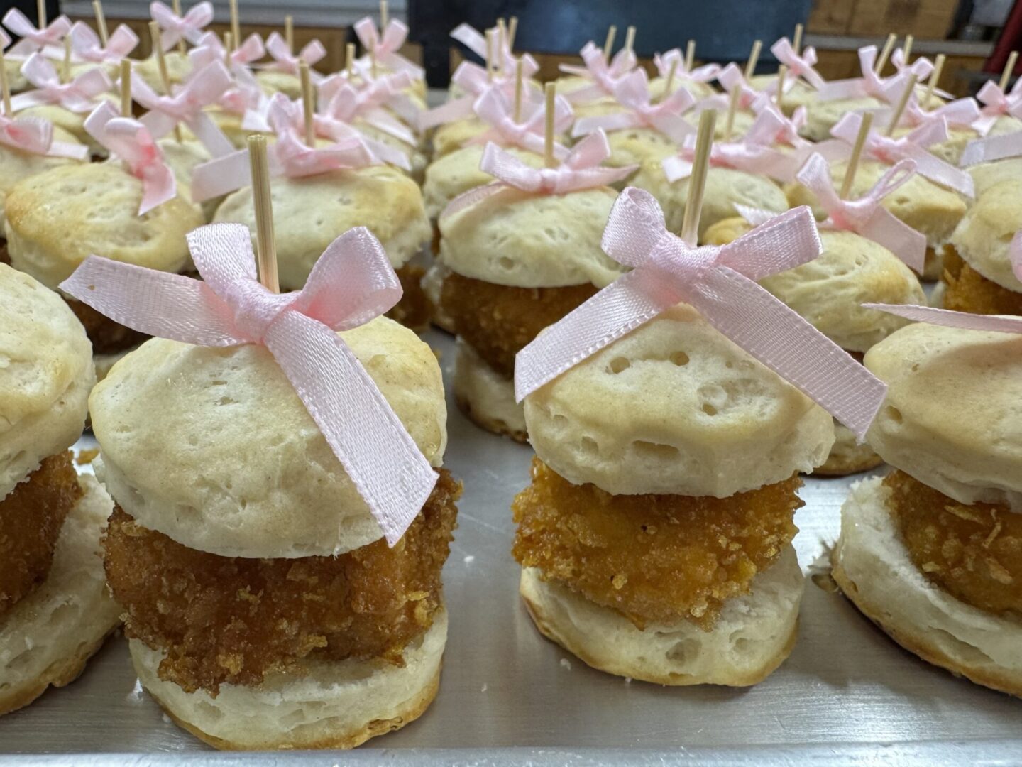 Mini carrot cake cupcakes with cream cheese frosting and pink bows on toothpicks.