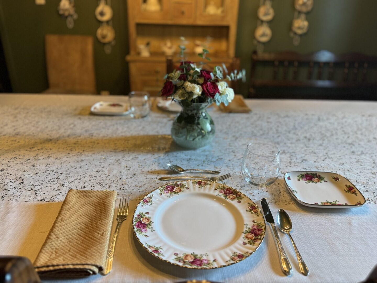 Elegant dining setup with floral china and fresh flowers in a cozy room.